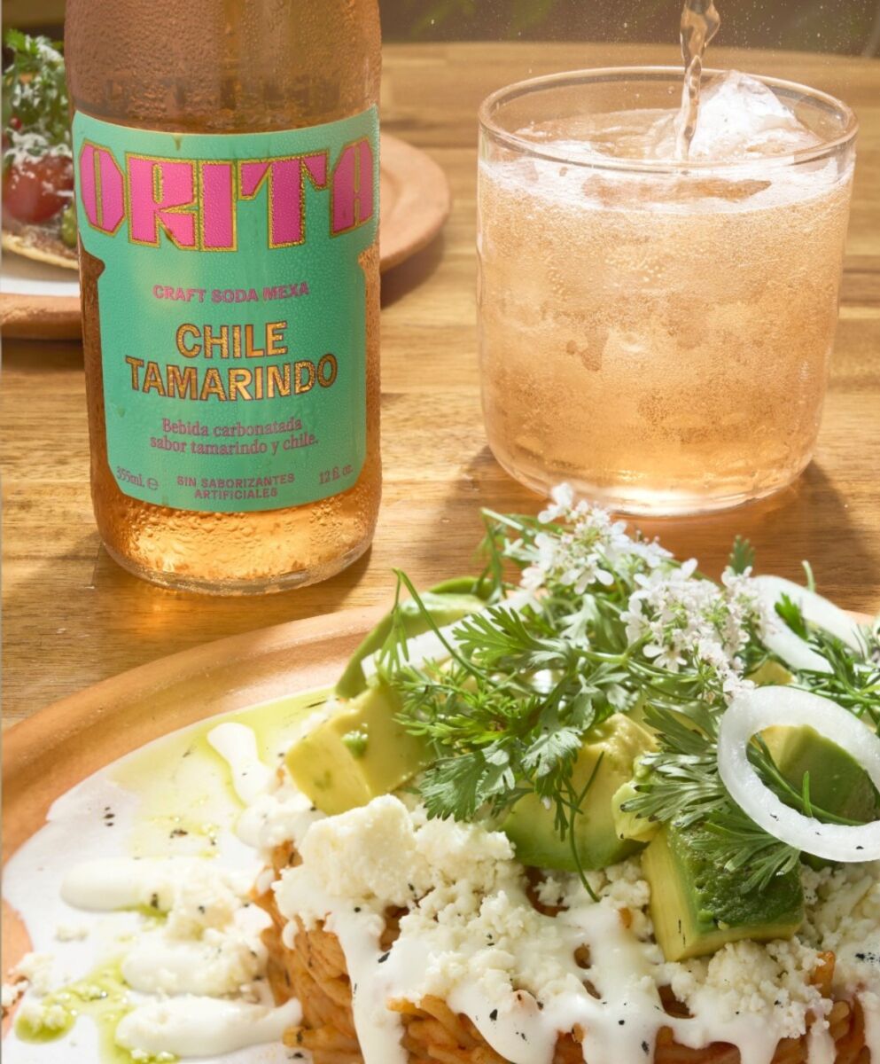 close up de un plato de comida mexicana con una botella de Orita chile-tamarindo y un vaso