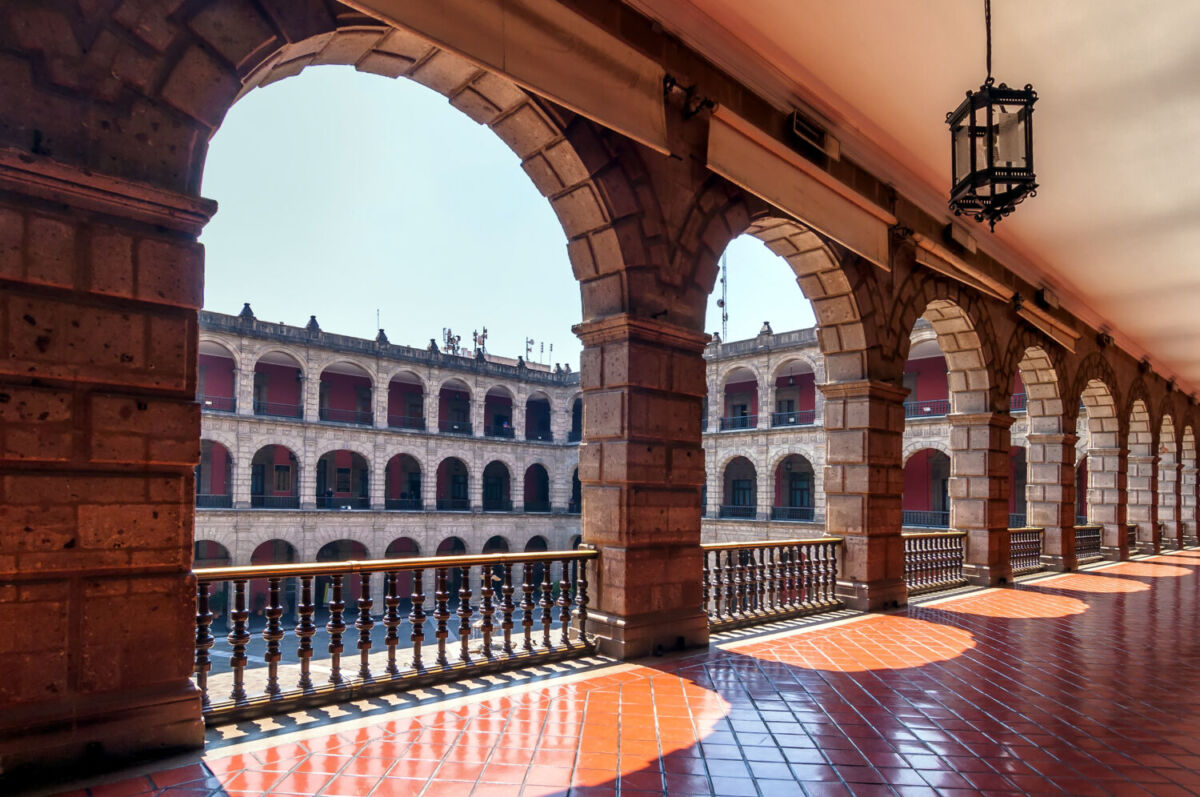 arcos de un edificio con palacio de fondo y cielo azul