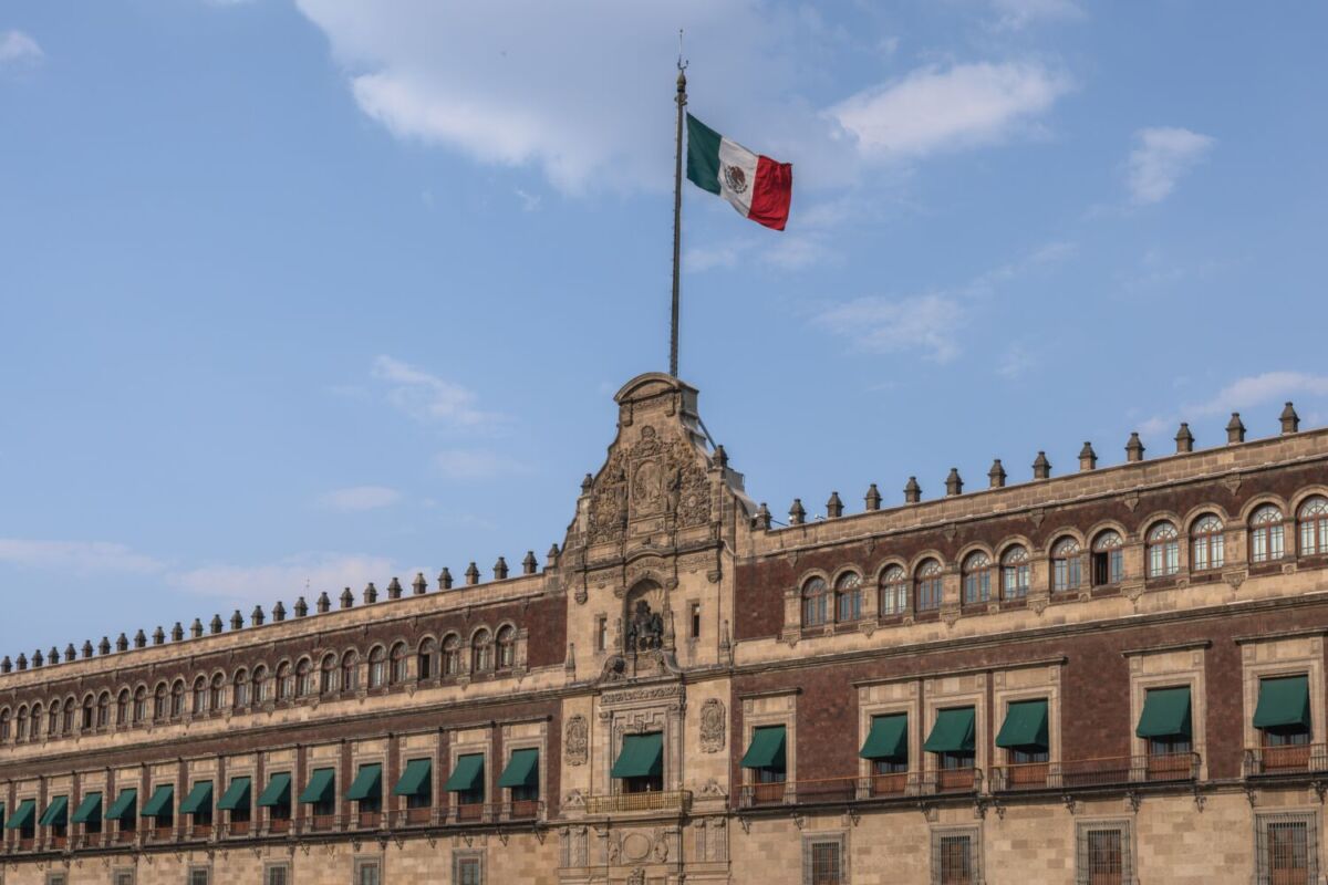 palacio de piedra con bandera mexicana y cielo azul
