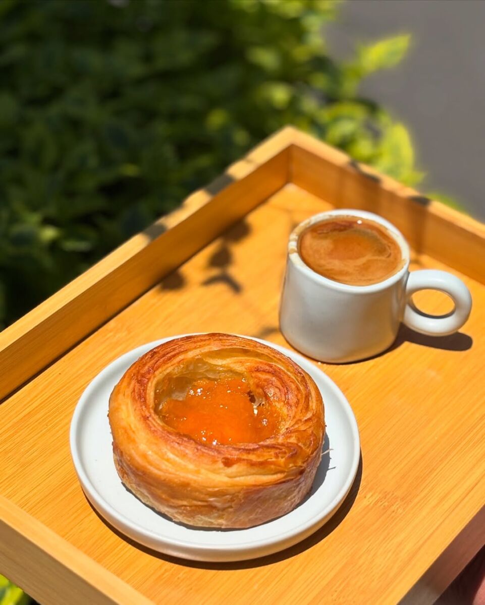 Charola de madera con un rol de guayaba y un café 