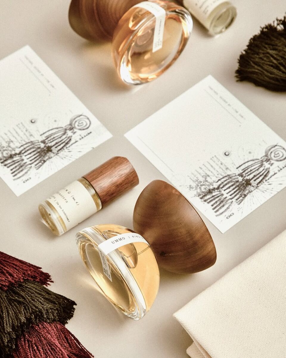 Perfume con botellitas y hojas de papel en fondo blanco