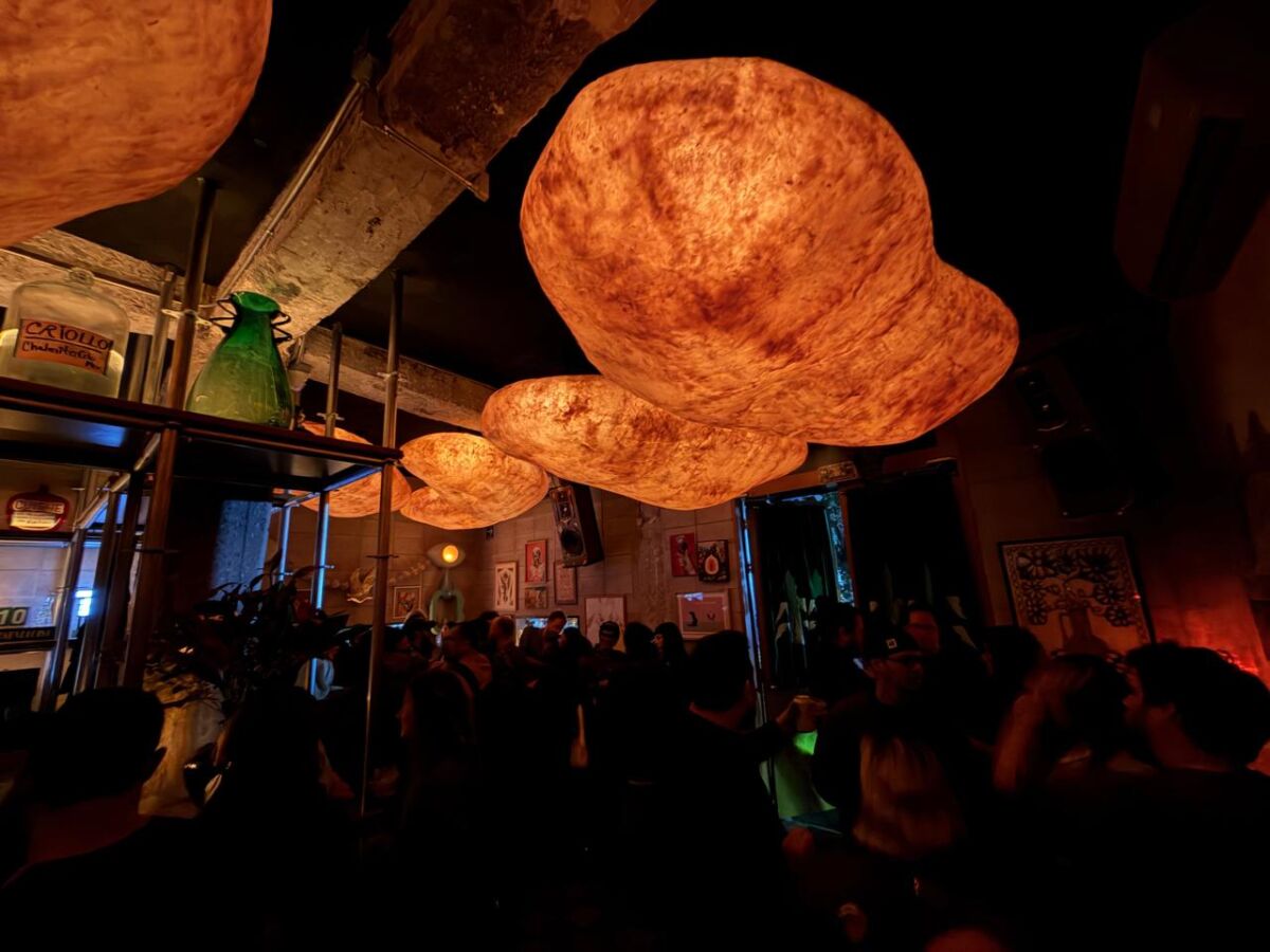 salón oscuro con mucha gente y lámparas grandes que simulan medusas amarillas