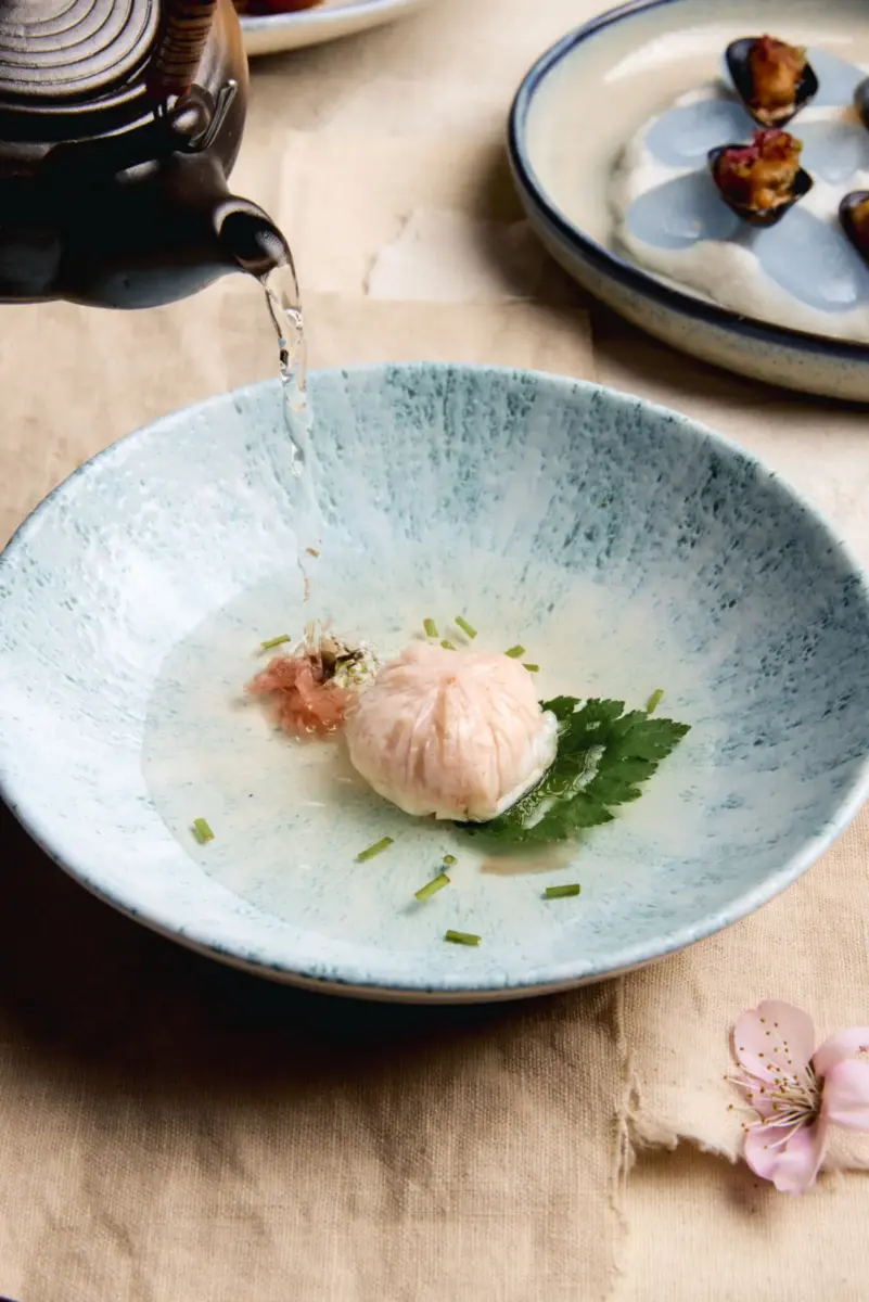 plato azul hondo con caldo claro y una esfera rosa