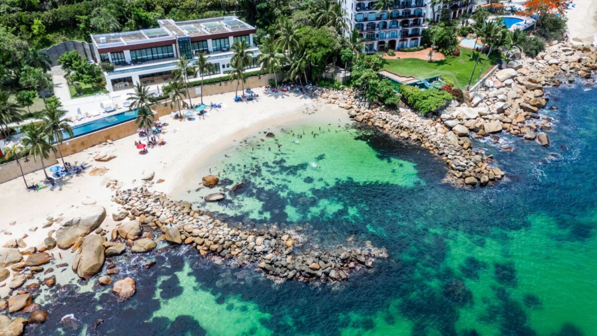 vista aérea de una playa esmeralda rodeada de hoteles 