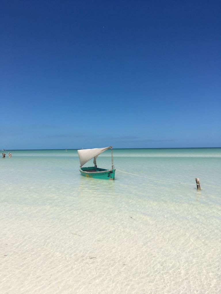 barco pequeño flotando en el agua tranquila y cristalina de playa bahamitas en campeche