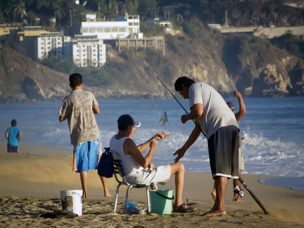 Una familia pescando a las orillas del mar en Pie de la Cuesta, Guerrero