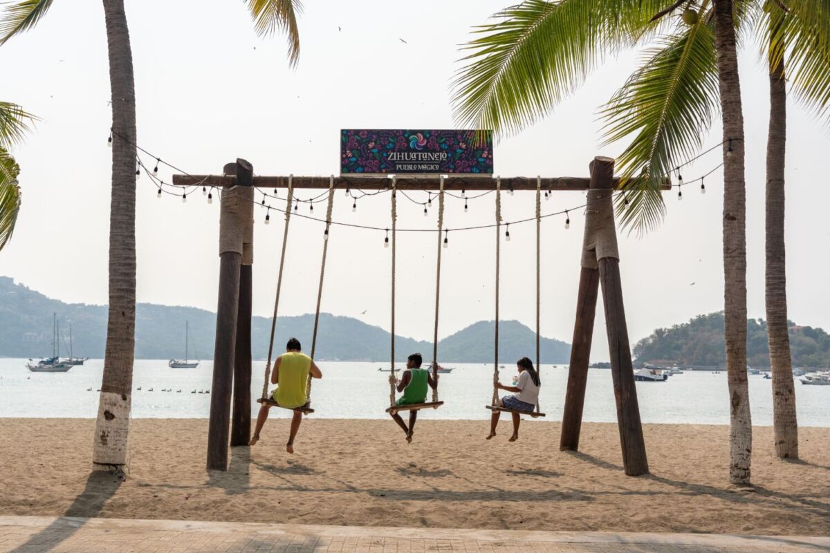 Niños disfrutando la playa en unos columpios con vista panorámica a la bahía de Ixtapa Zihuatanejo