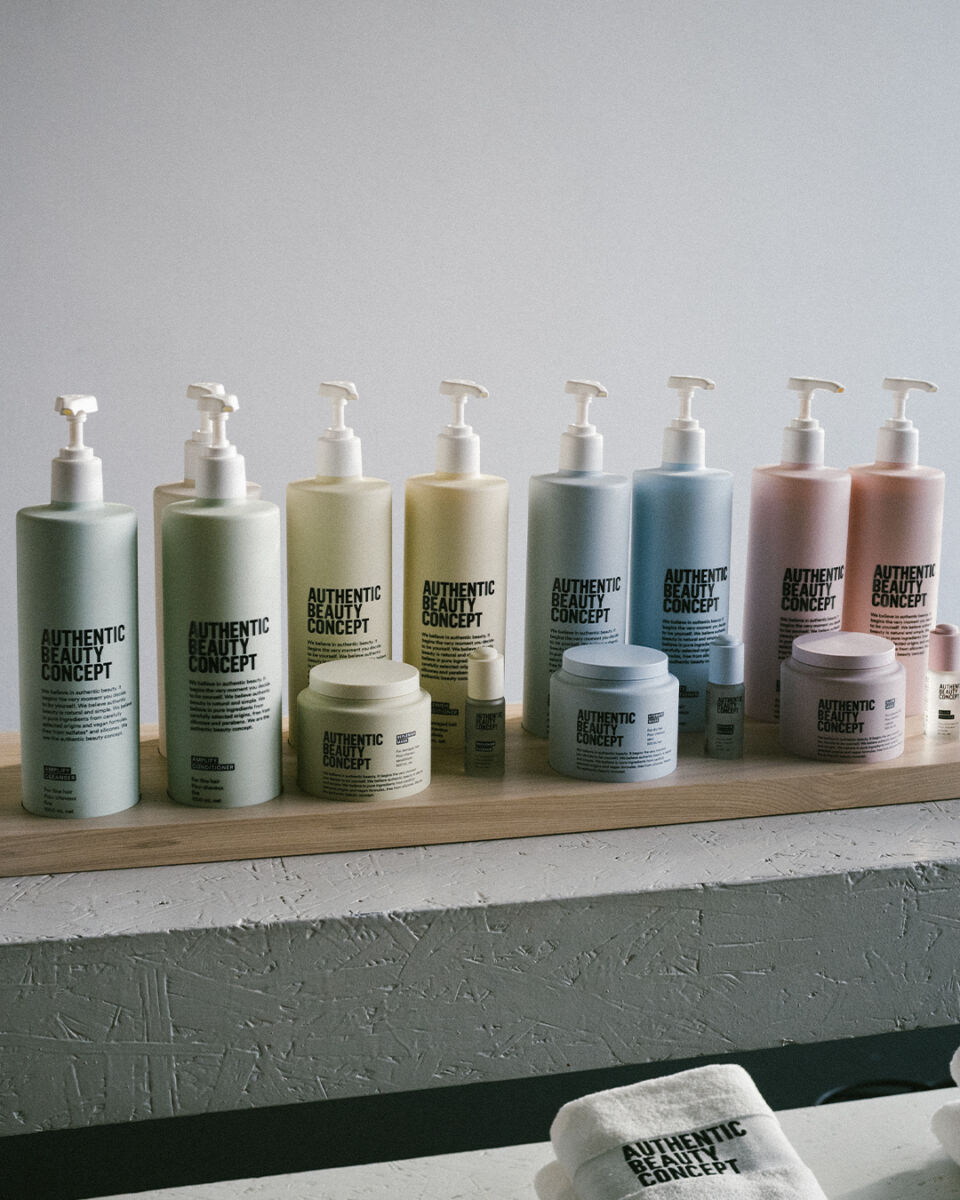 ocho botellas de plástico de colores pastel con dispensadores colocadas sobre una repisa