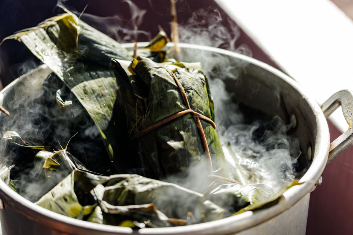 tamales envueltos en hoja de plátano metidos en una olla de vapor 
