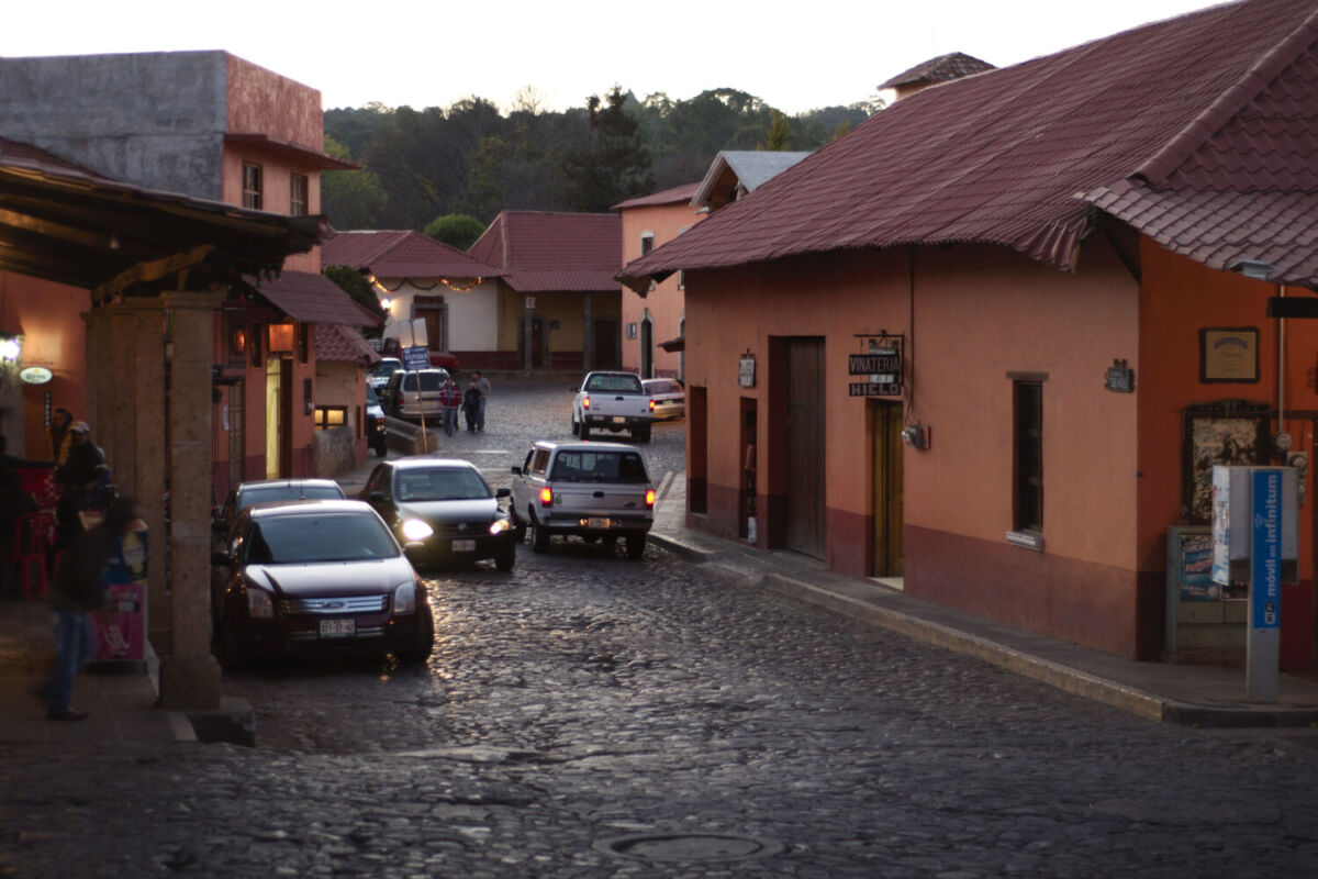 autos pasando por una calle adoquinada de un pintoresco pueblo