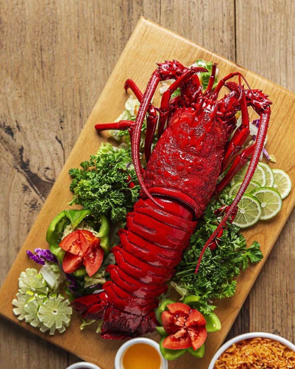 langosta completa sobre una tabla de madera con vegetales