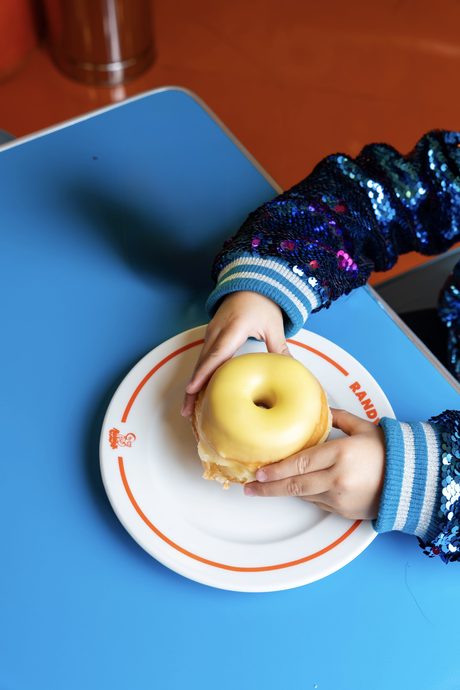 manos de un niño agarrando una dona sabor piña 