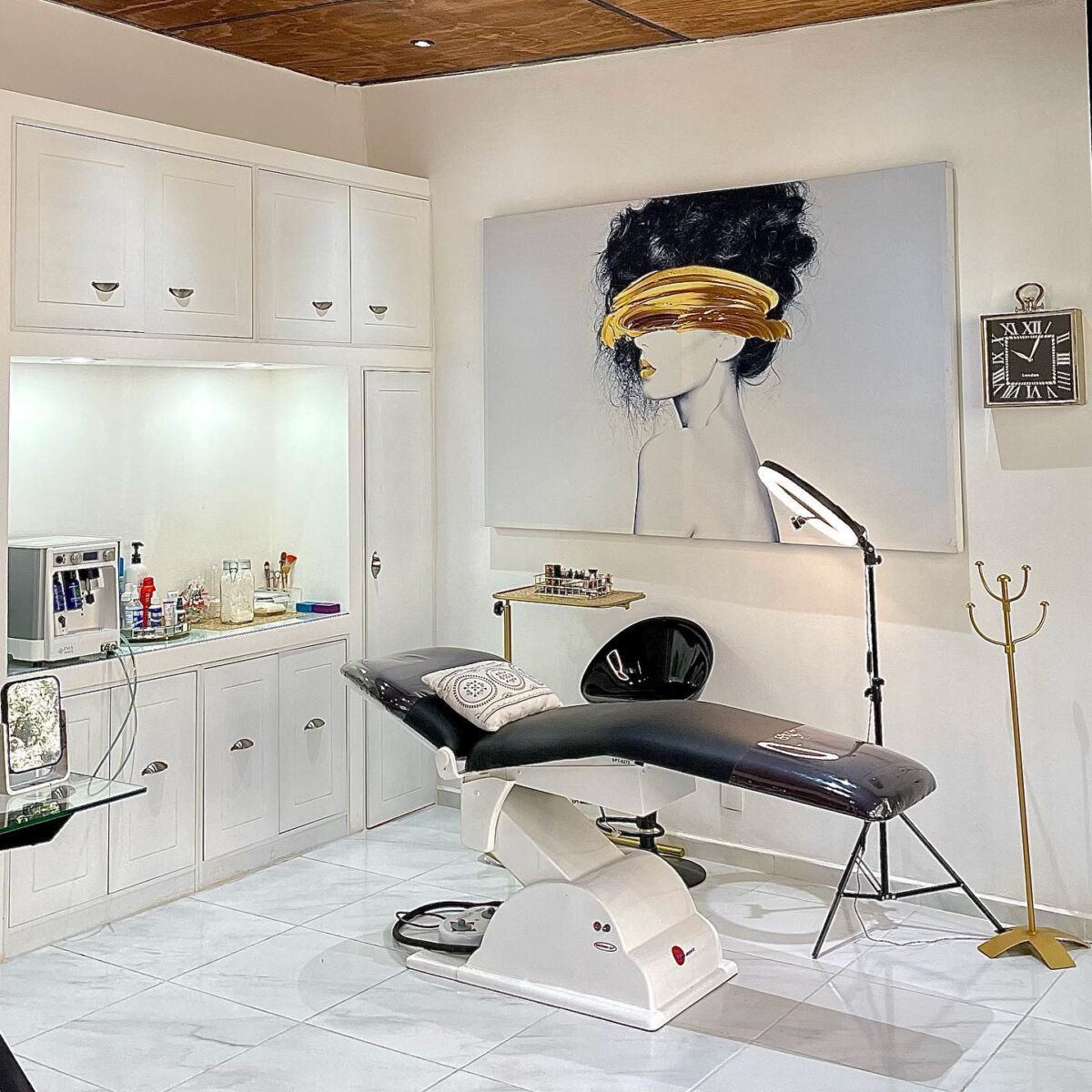 habitación blanca con un cuadro de una mujer y una camilla negra bahorrinas un aro de luz