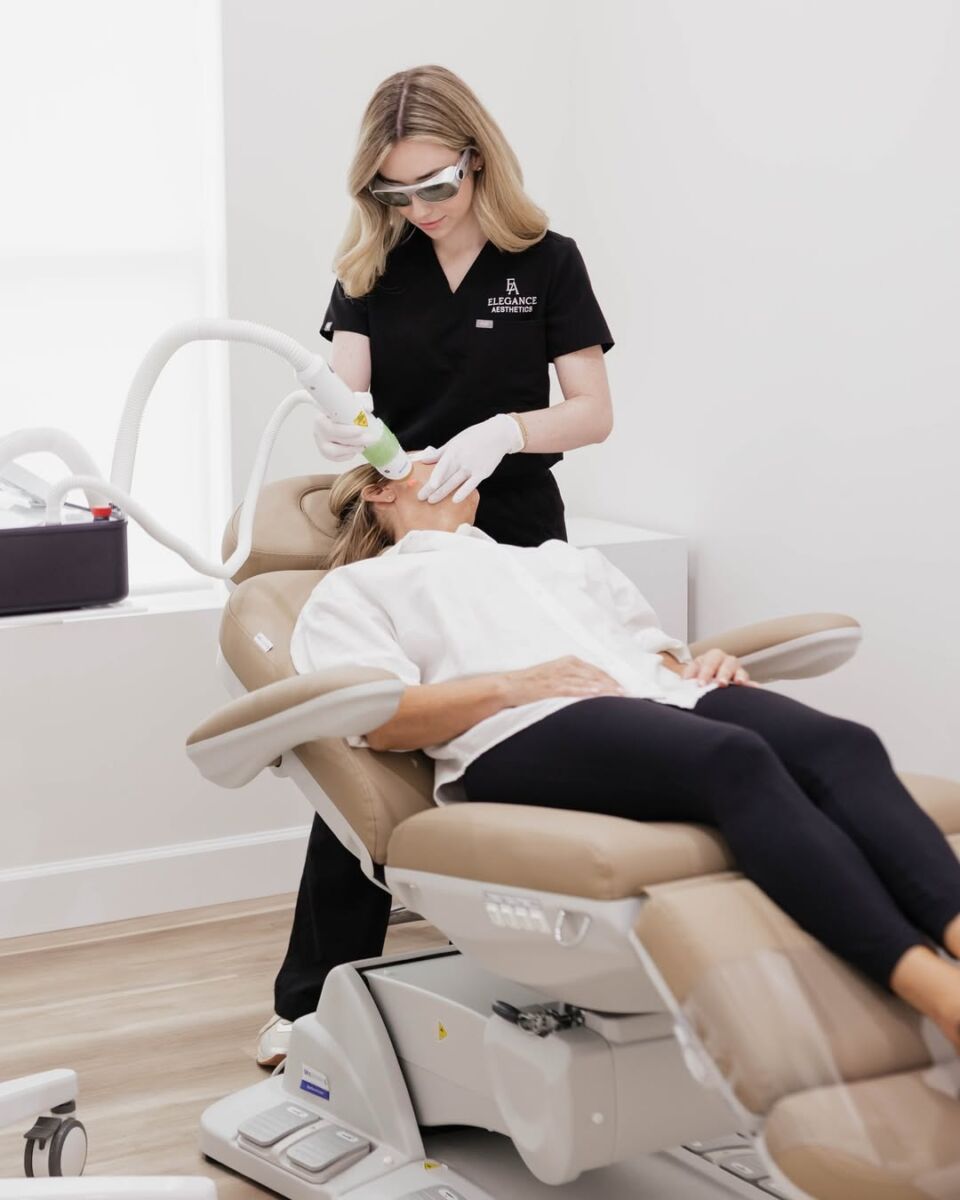 doctora rubia vestida de negro con lentes especiales hacendo un tratamiento facial con láser a una paciente sentada en un sillón reclinable