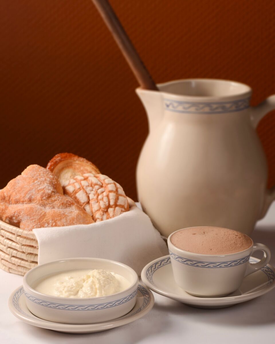 canas con pan, nata y una jarra con chocolate caliente 
