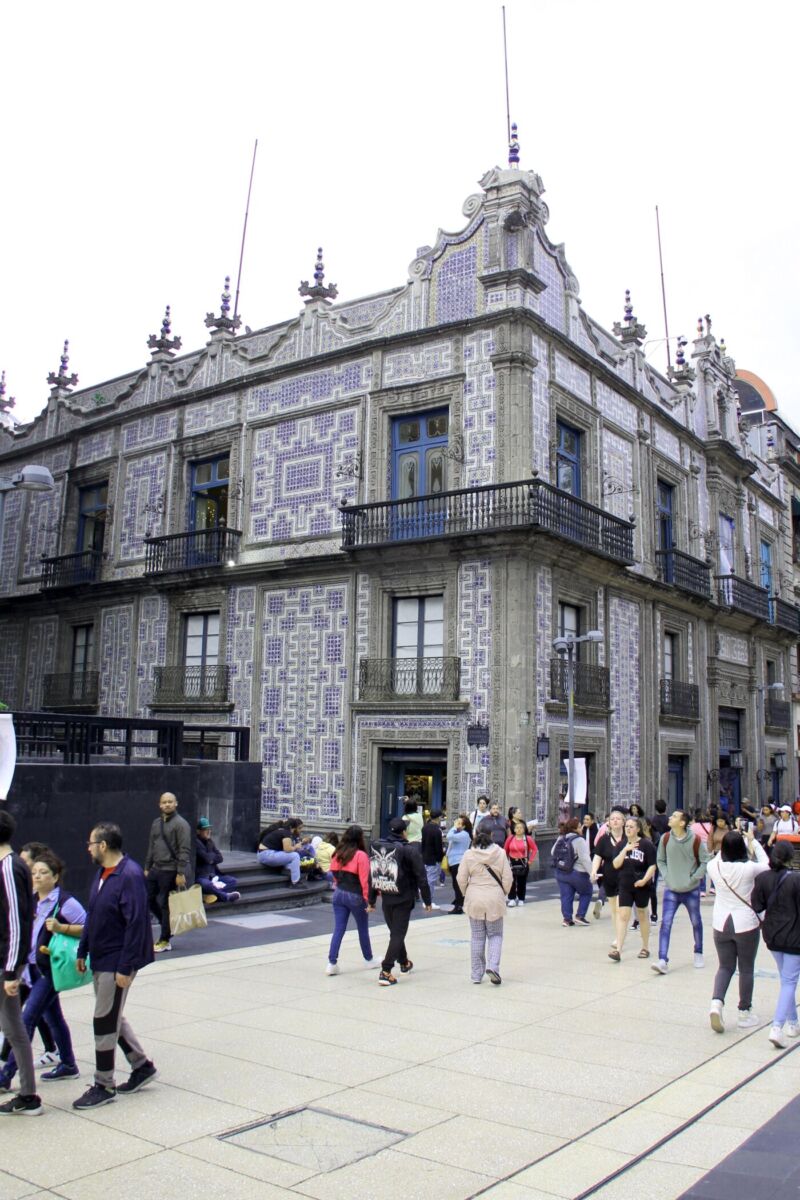 Fachada de la Casa de los Azulejos con gente cruzando por la calle peatonal. 