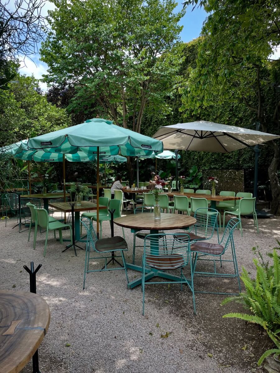 mesas, sillas y sombrillas en un jardín