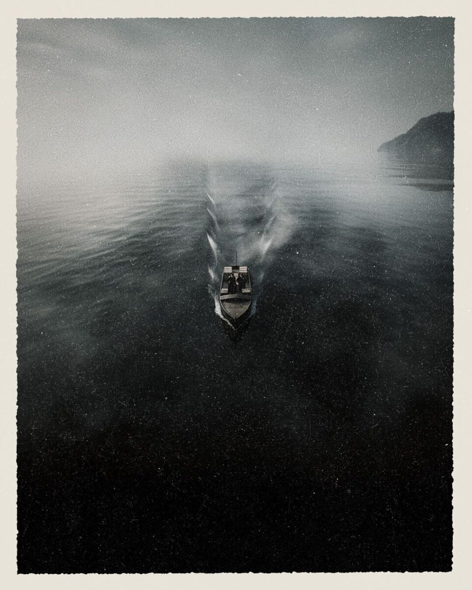 toma aérea en blanco y negro de un barco pequeño cruzando el mar