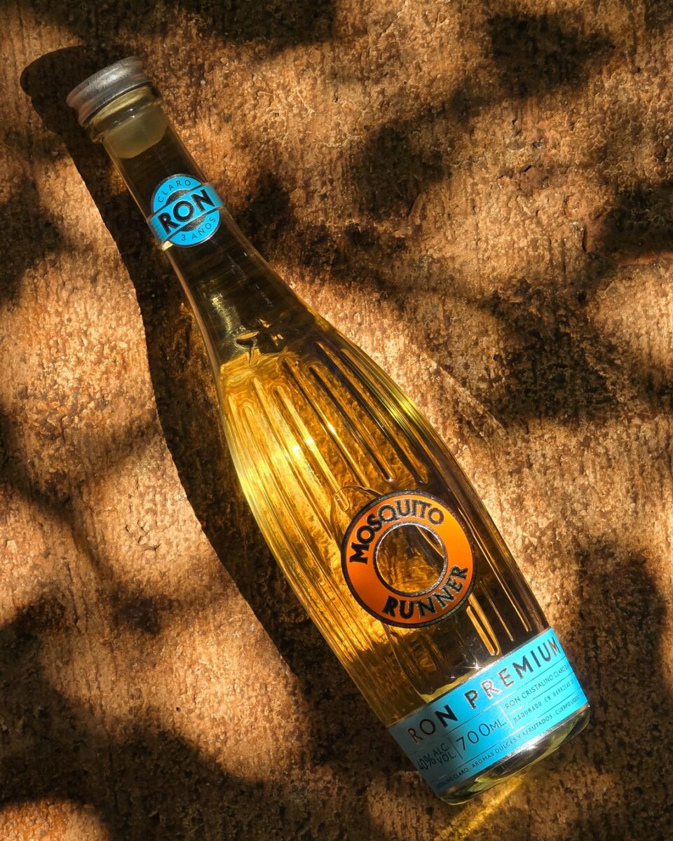 botella de cristal con etiqueta azul sobre la arena