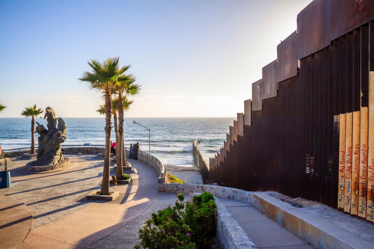 paisaje del mar con el muro de la frontera entre méxico y eua a la derecha