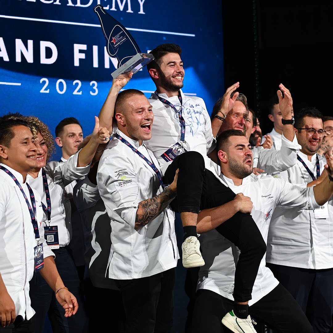 grupo de chefs jóvenes alzando en brazos al ganador de San Pellegrino Young Chef con un trofeo