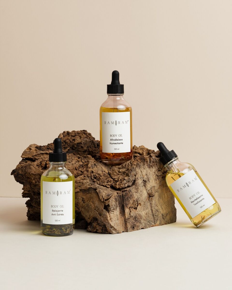 tres botellas de cristal con gotero apoyadas en un tronco de árbol