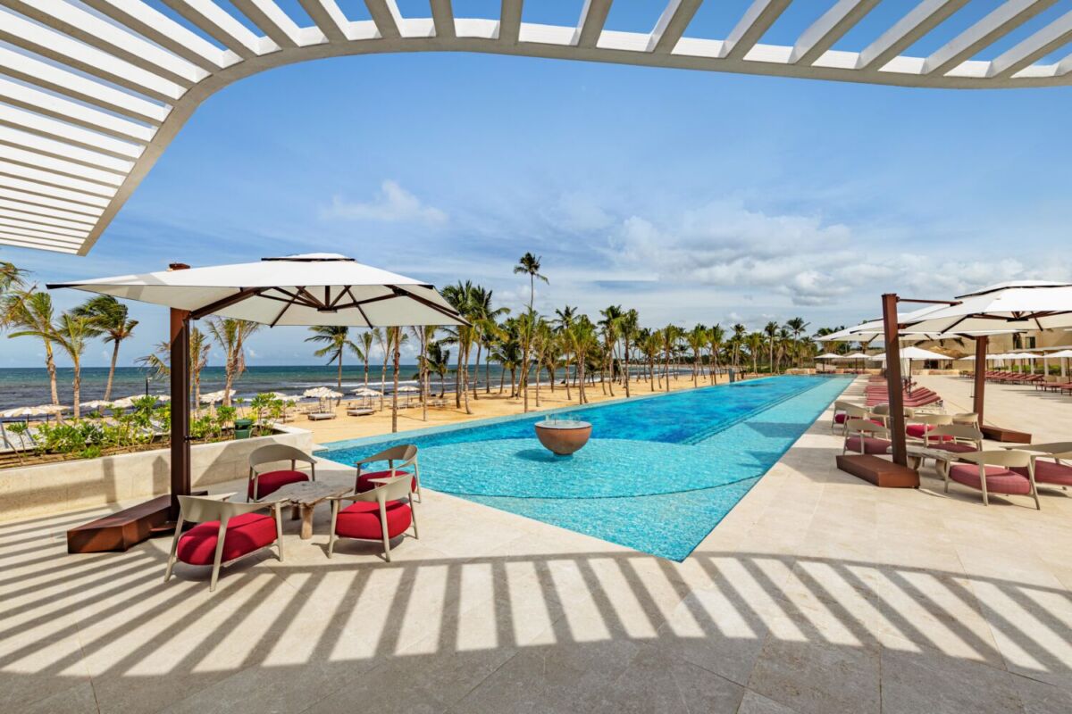 piscina rodeada de mesas y sillas, cerca del mar 