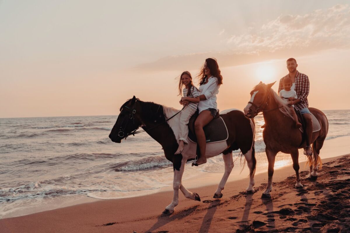 una familia paseando en caballo por la playa