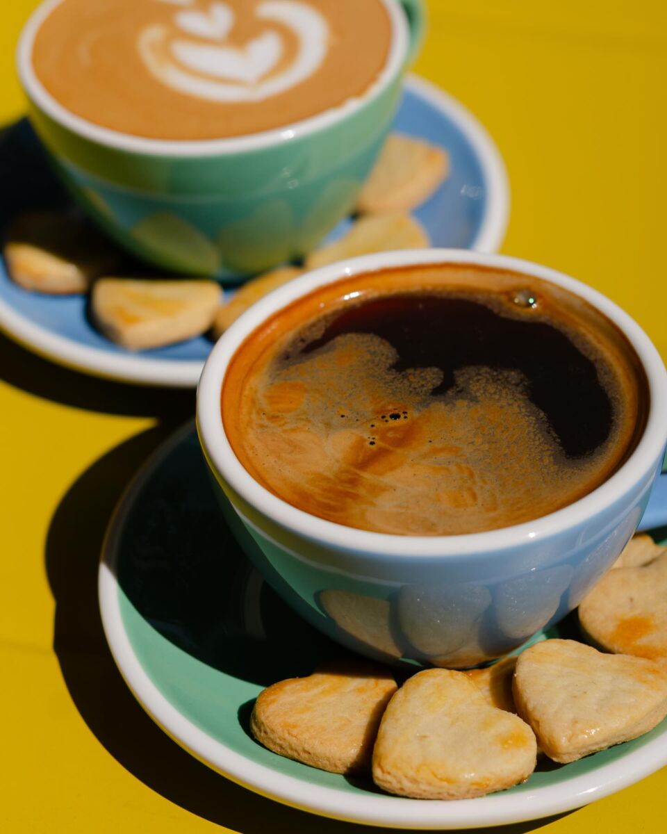 café americano y latte en tazas de colores pastel con galletas en forma de corazón