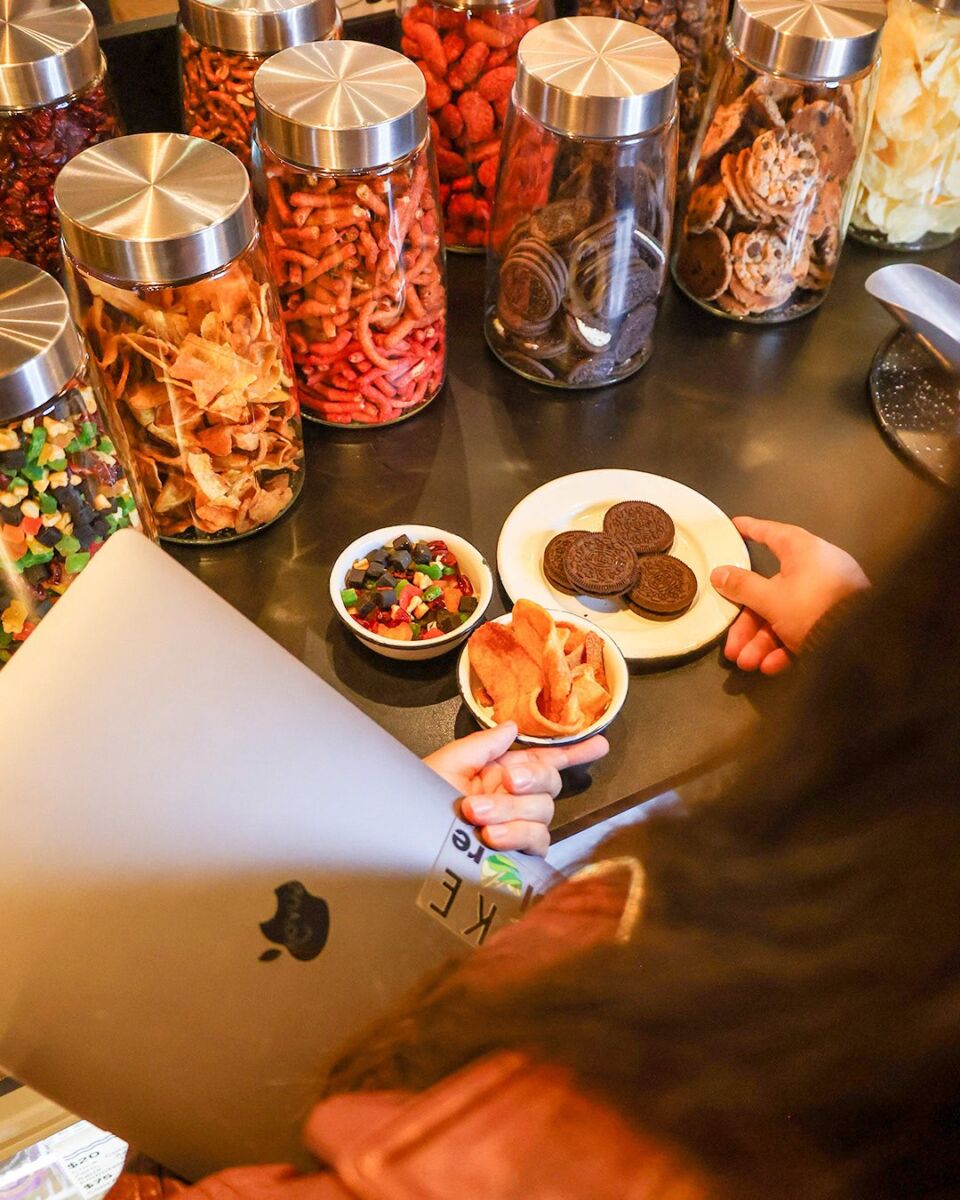 mujer sirviéndose comida con una mano y sosteniendo una computadora portátil con la otra