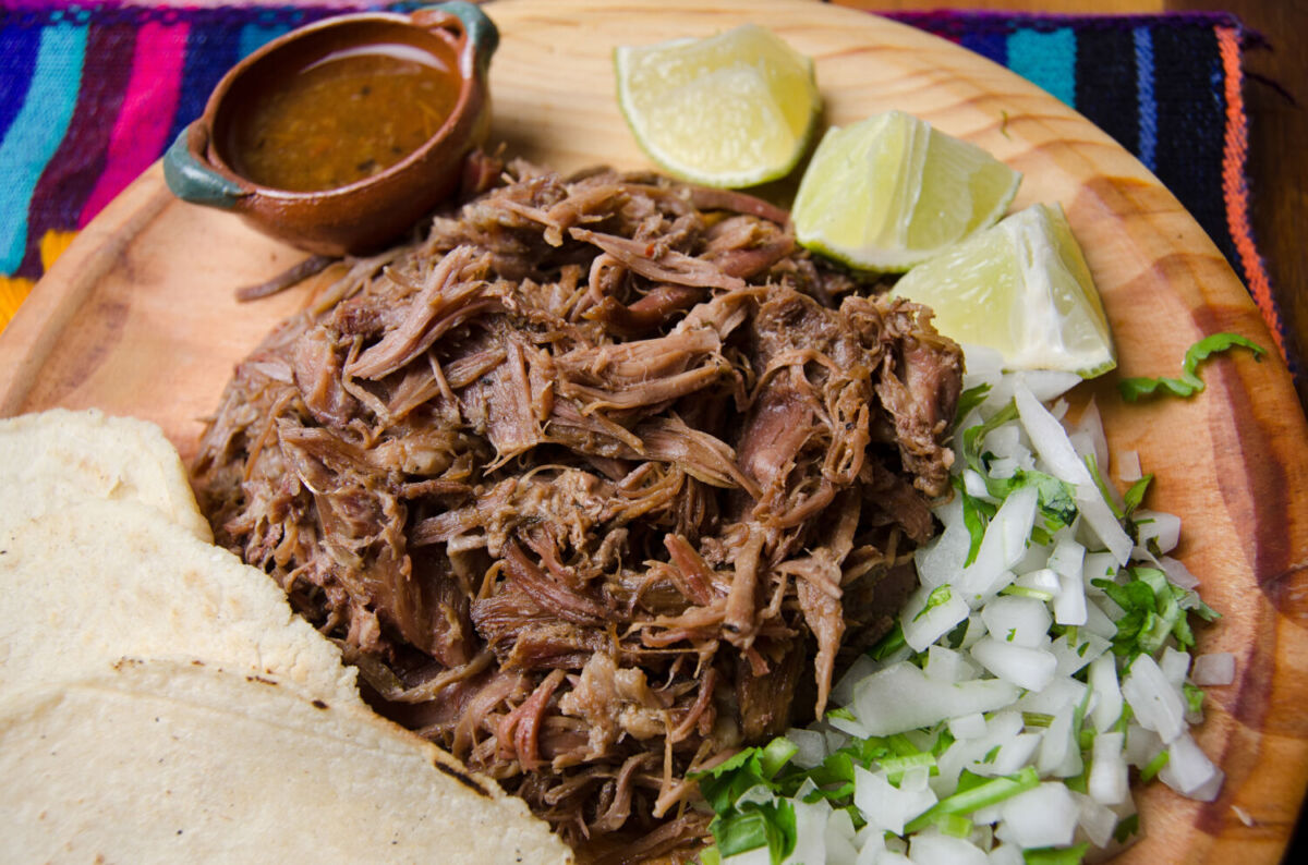 plata de madera con barbacoa de borrego, cebolla y cilantro 