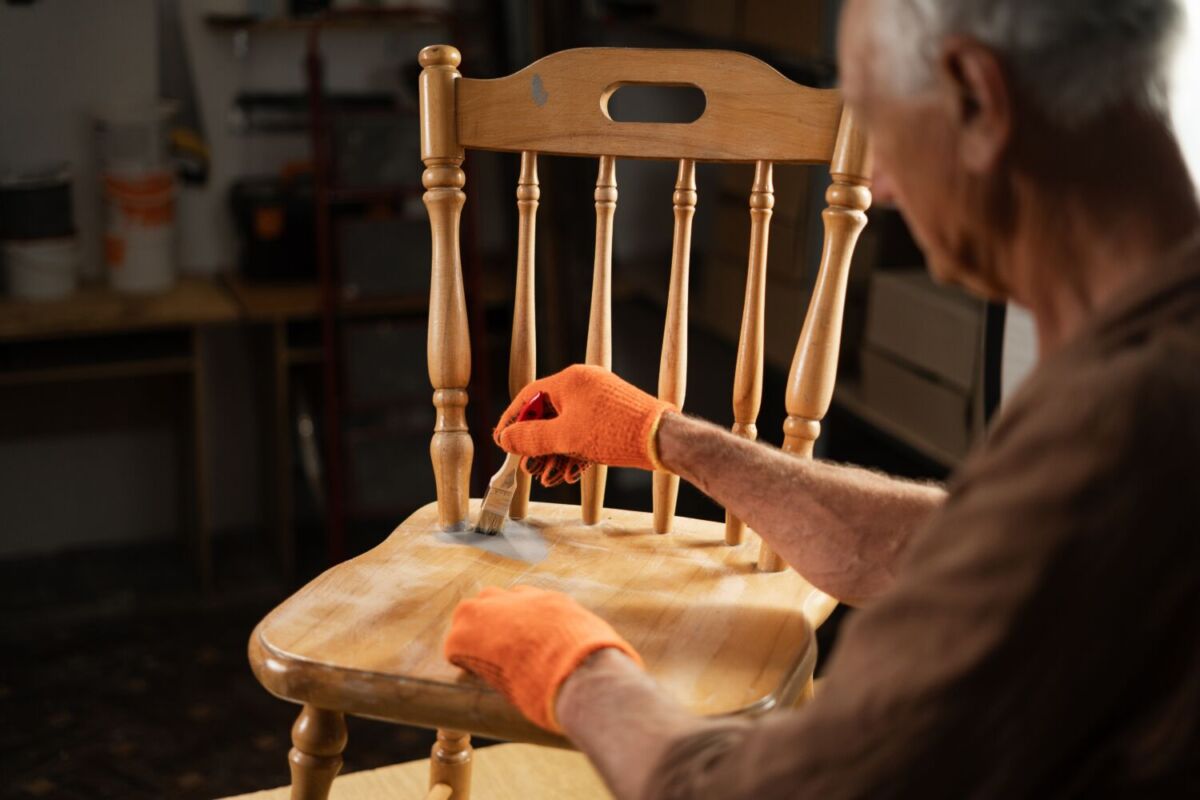 hombre pintando a mano una silla de madera