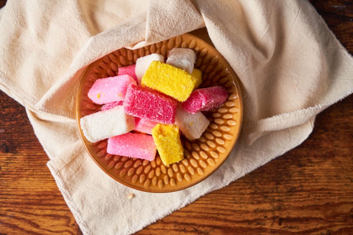Dulces típicos poblanos borrachitos de colores en plato de madera con textil mexicano de fondo, Puebla, México