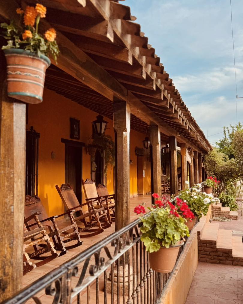 casa tradicional mexicana naranja con porche con flores y mecedoras