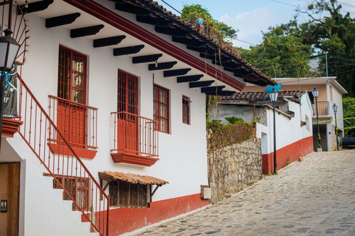 calle empedrada con casa de fachada blanca y tejas rojas