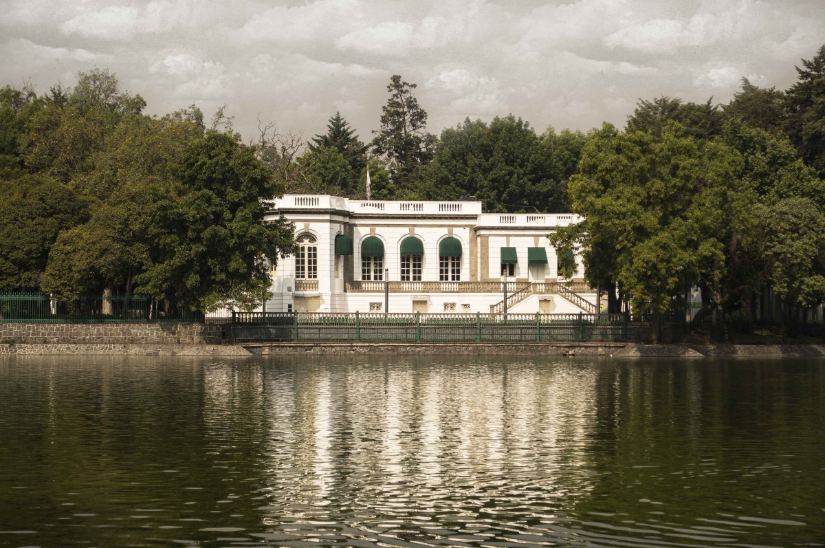 casona blanca entre los árboles frente a un lago