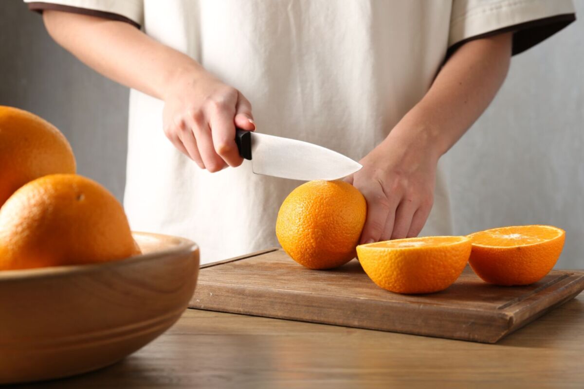 personan cortando naranjas en una tabla de madera 