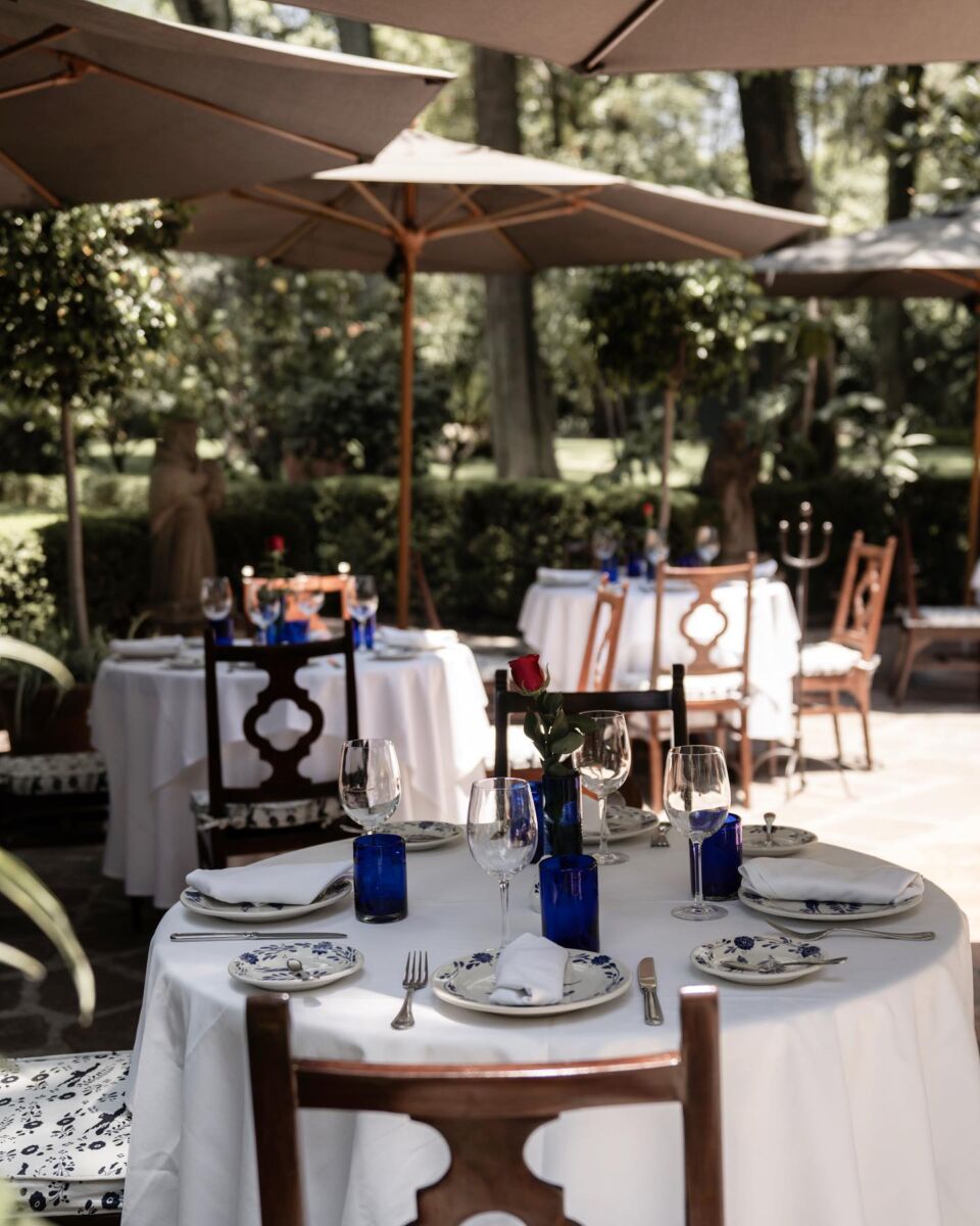 Terraza del restaurante San Ángel Inn con mesas con mantel blanco, sombrillas y jardín arbolado, Ciudad de México