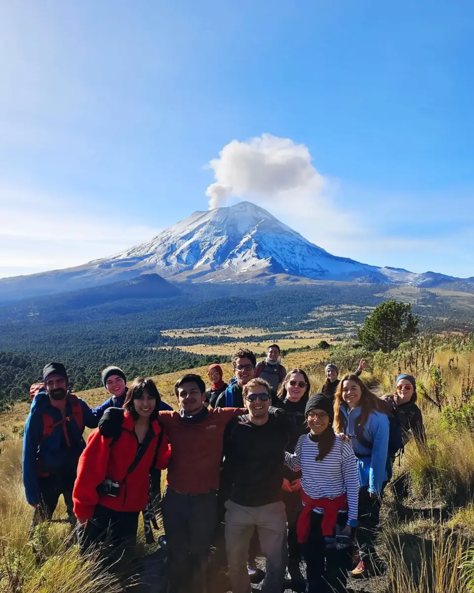 grupo de senderistas frente al volcán popocatépetl con fumarola