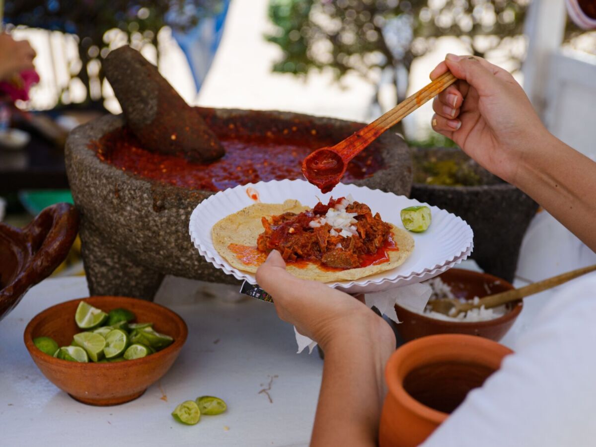 persona echando salsa a su taco hecha en un molcajete 