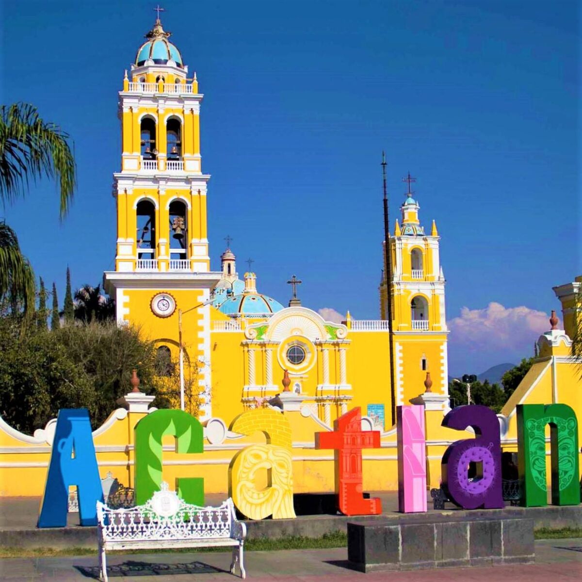 letras de colores frente a la iglesia amarilla de acatlan de osorio, puebla