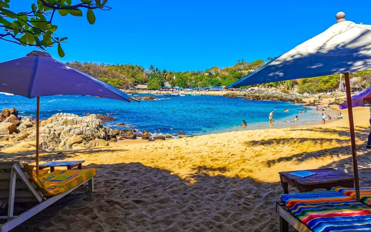 día soleado en una bahía con arena dorada, camastros y sombrillas