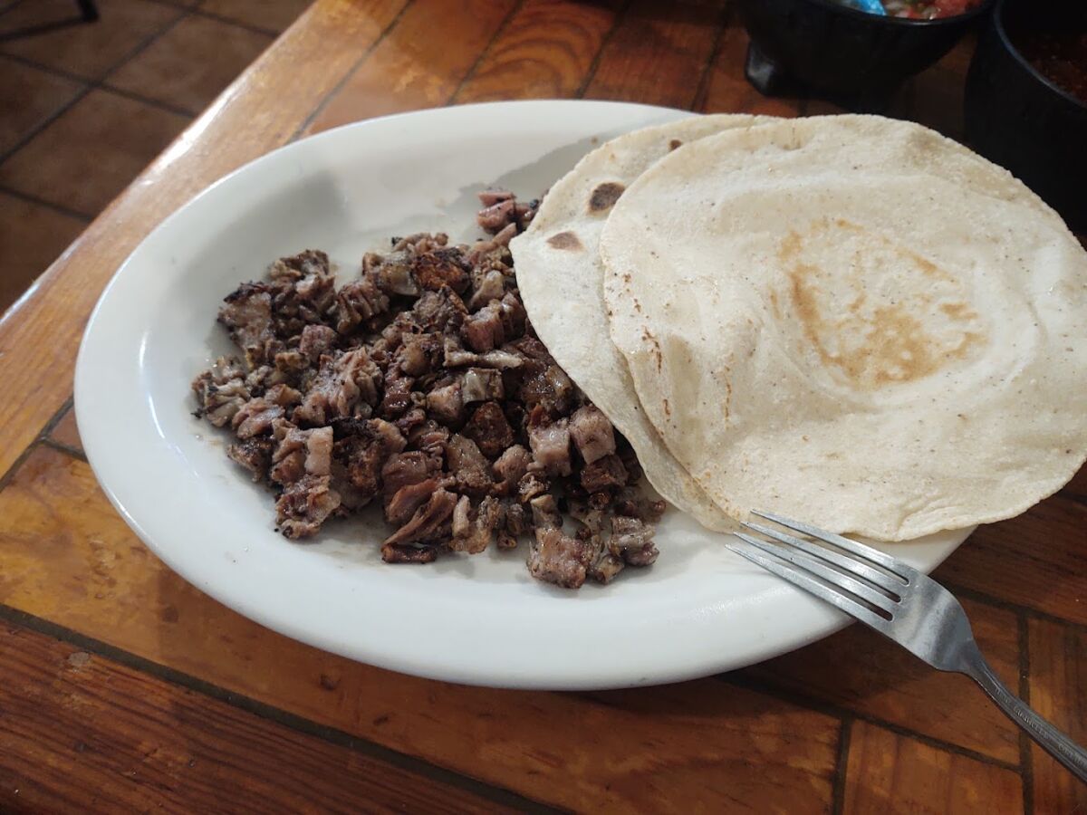 sobre un plato carne asada acompañado de tortillas de harina