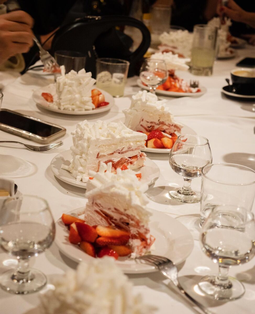 mesa despues de comer con platos de merengue con fresas y copas a la mitad