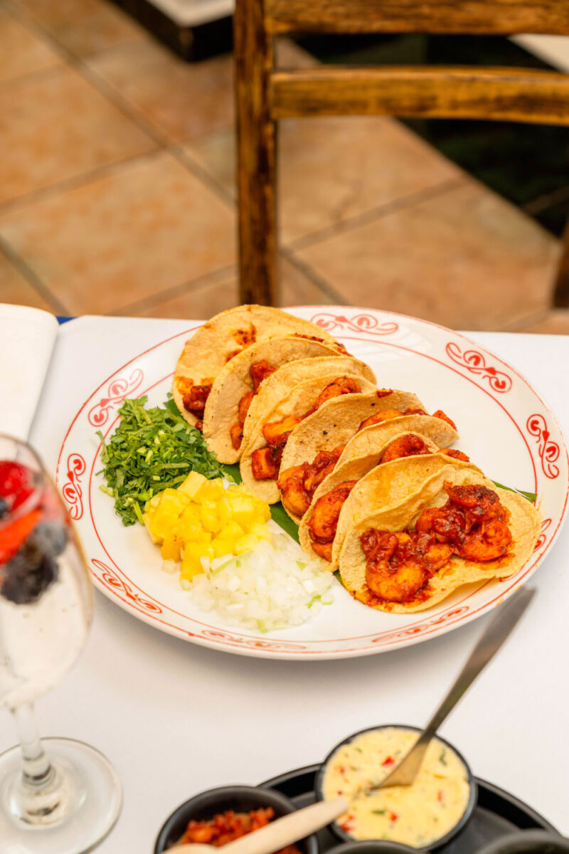 plato de tacos de pescado al pastor con cilantro, cebolla y piña picados a un costado