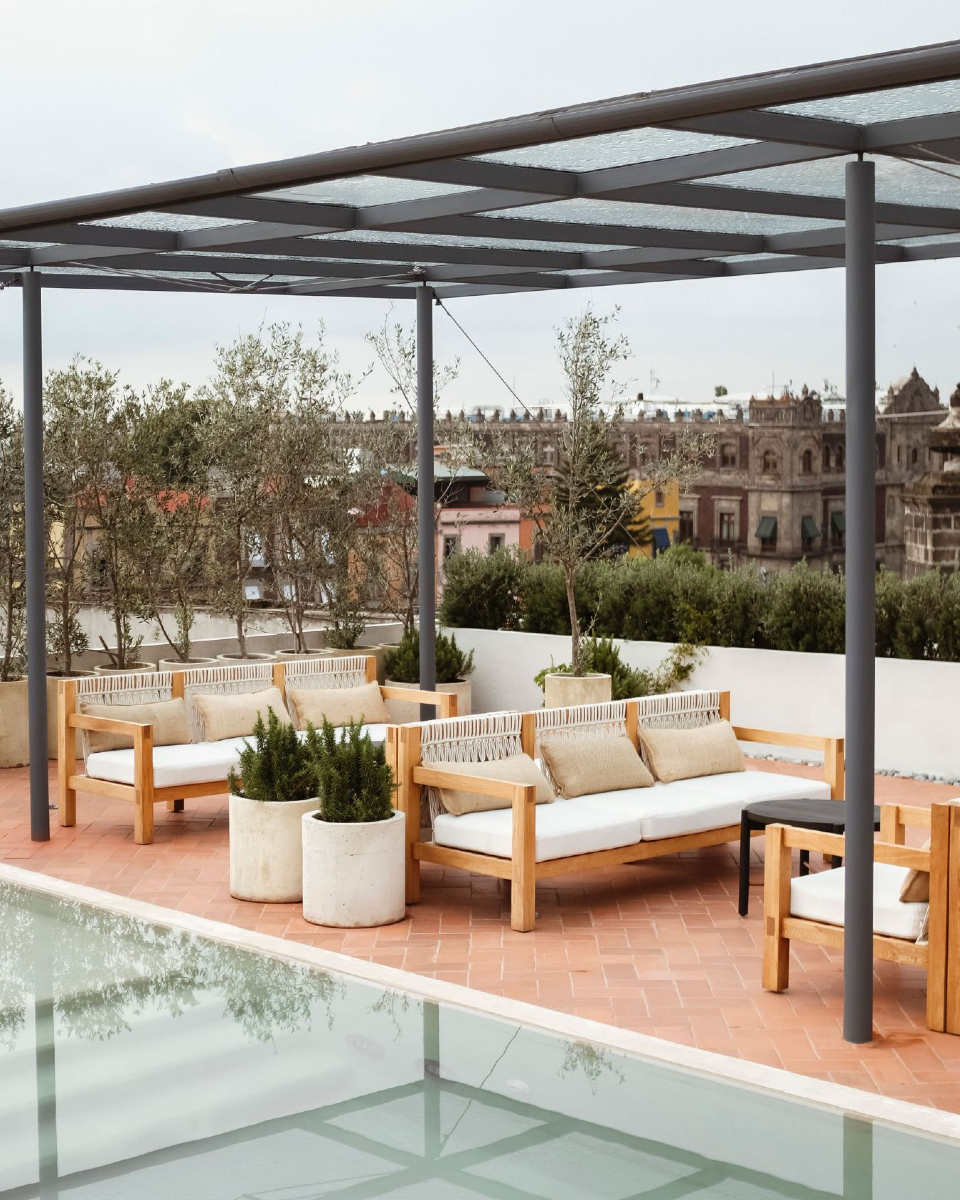 sillones blancos junto a una alberca y vistas al centro histórico de cdmx