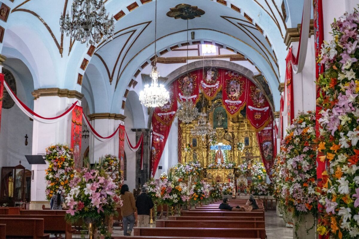 interior de una iglesia mexicana con retablo dorado y decoracion con flores