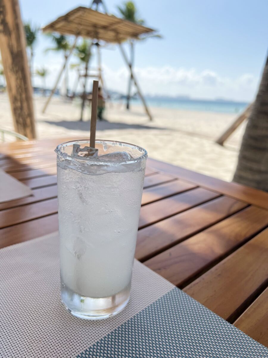 Vaso de suero en la playa: agua mineral con limón y sal