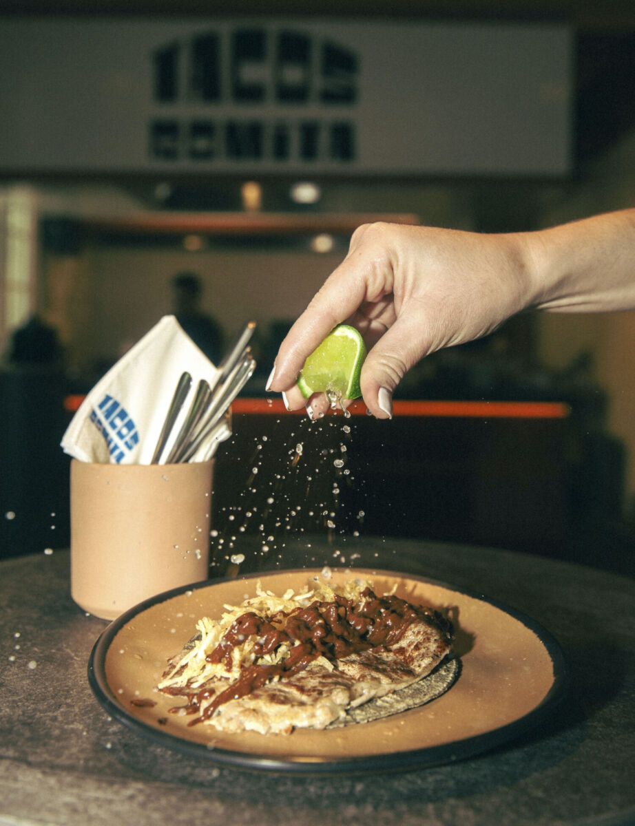 Una mano exprimiendo un limón a un taco de rib eye en La Romita, CDMX