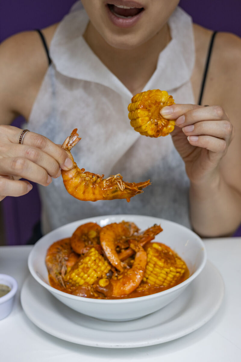 mujer comiendo camarones con elote amarillo 